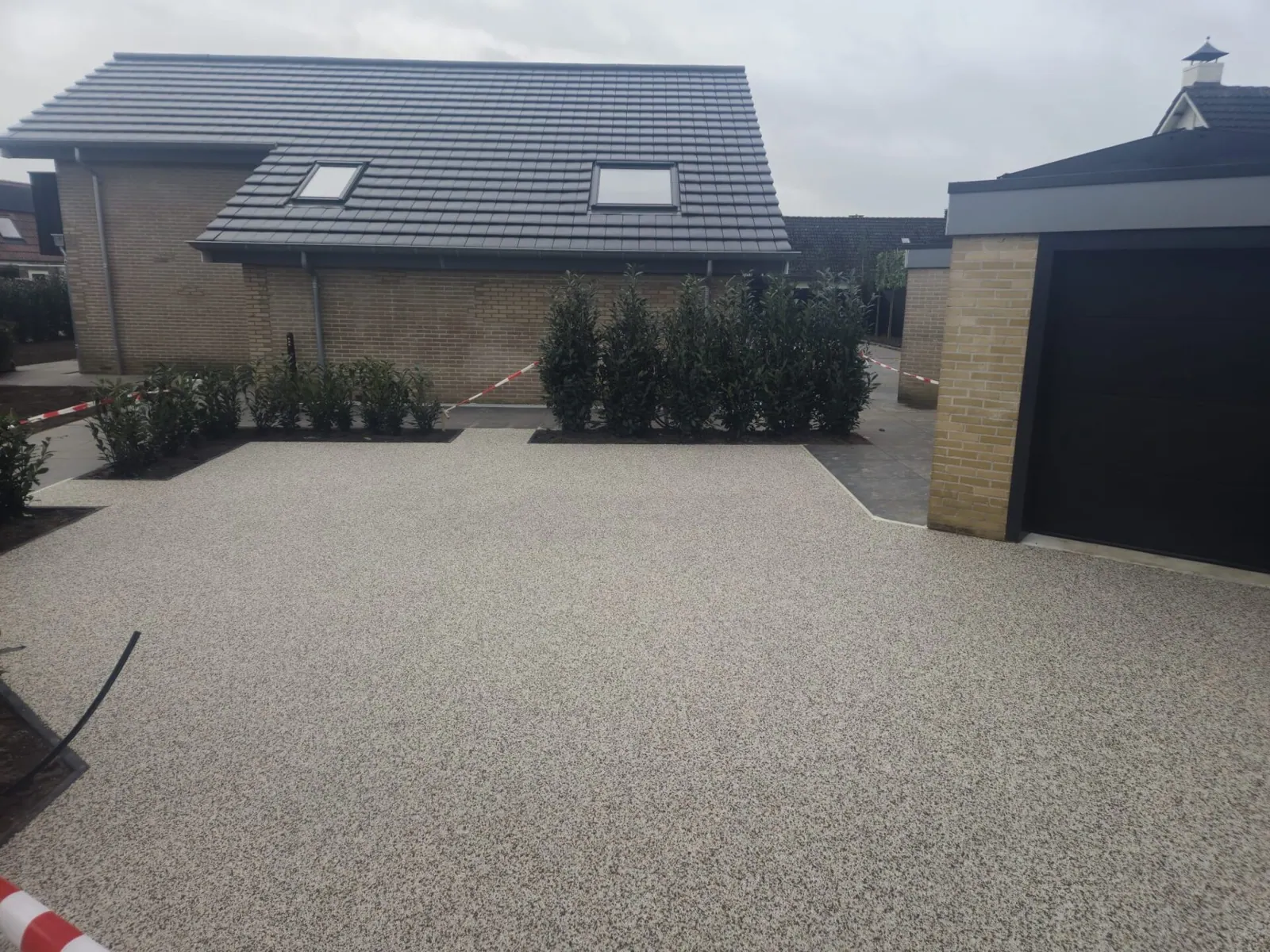 Brede oprit van lichtgrijs harsgebonden grind voor een woning met garage