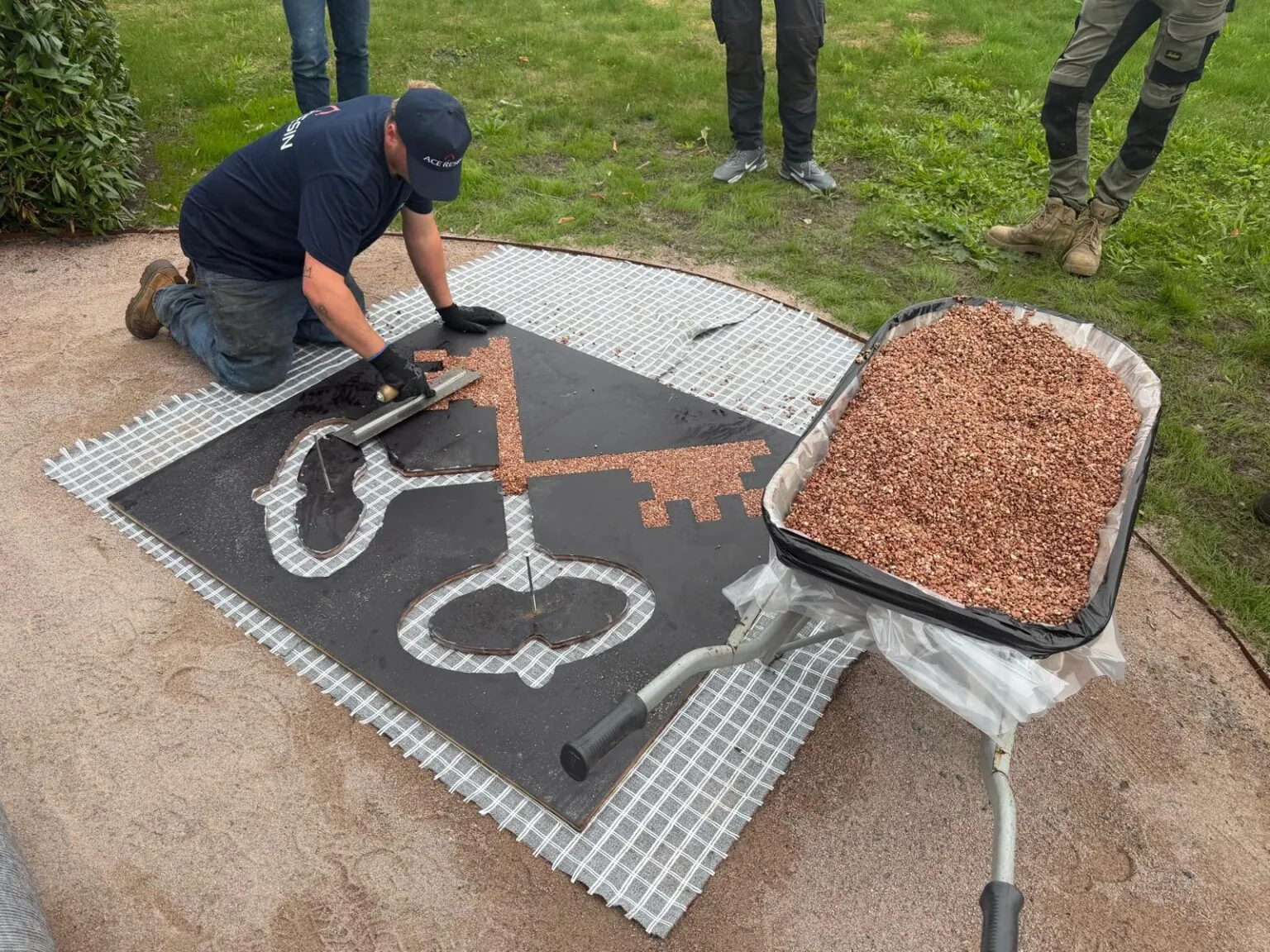 Een vakman van Step Stones legt een logo in met harsgebonden grind in meerdere kleuren