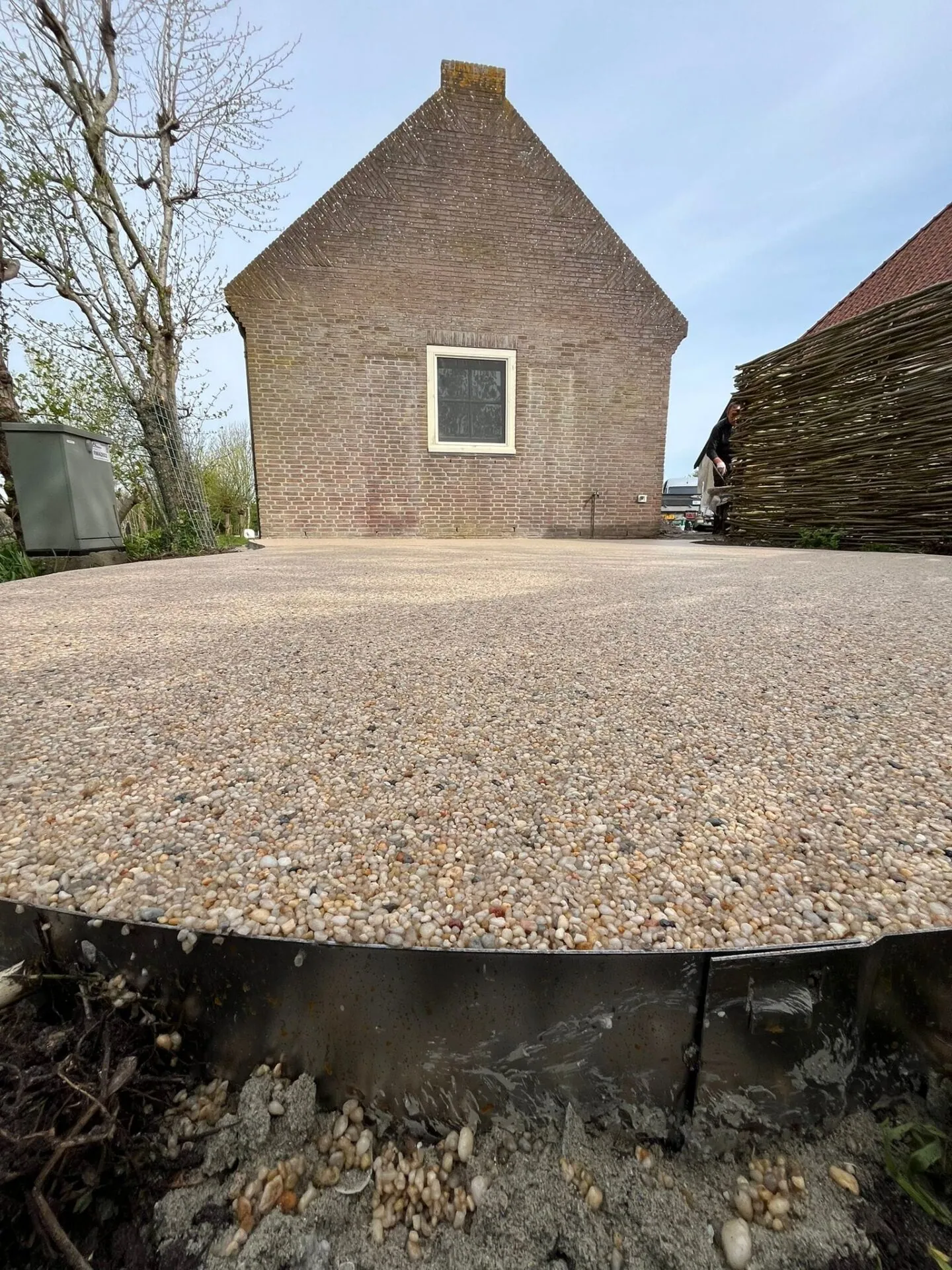 Groot vlak van harsgebonden grind voor een oude schuur op het platteland.