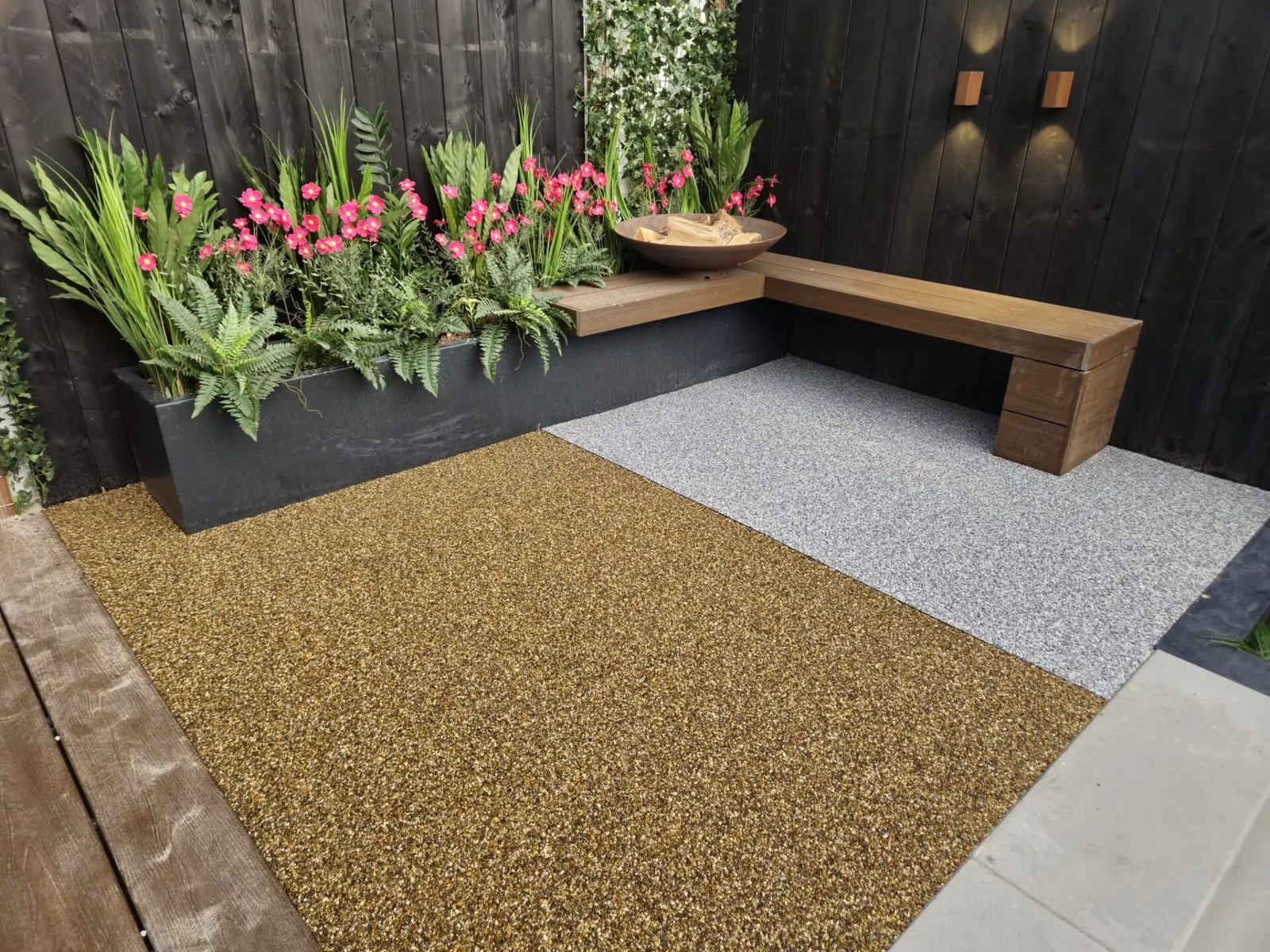 Twee vlakken harsgebonden grind naast elkaar, een warm goud en een lichtgrijs, bij een houten zitbank.