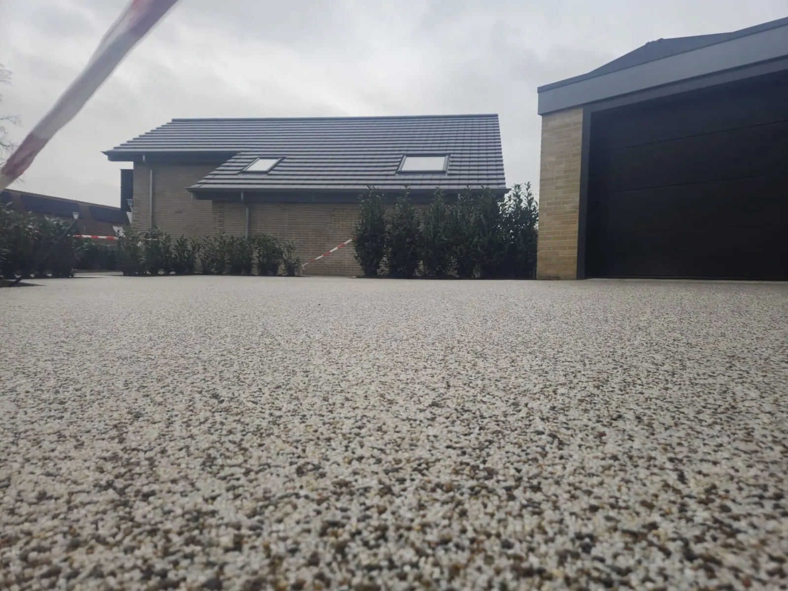 Lage close-up van een grindvloer met op de achtergrond woningen en een garage.