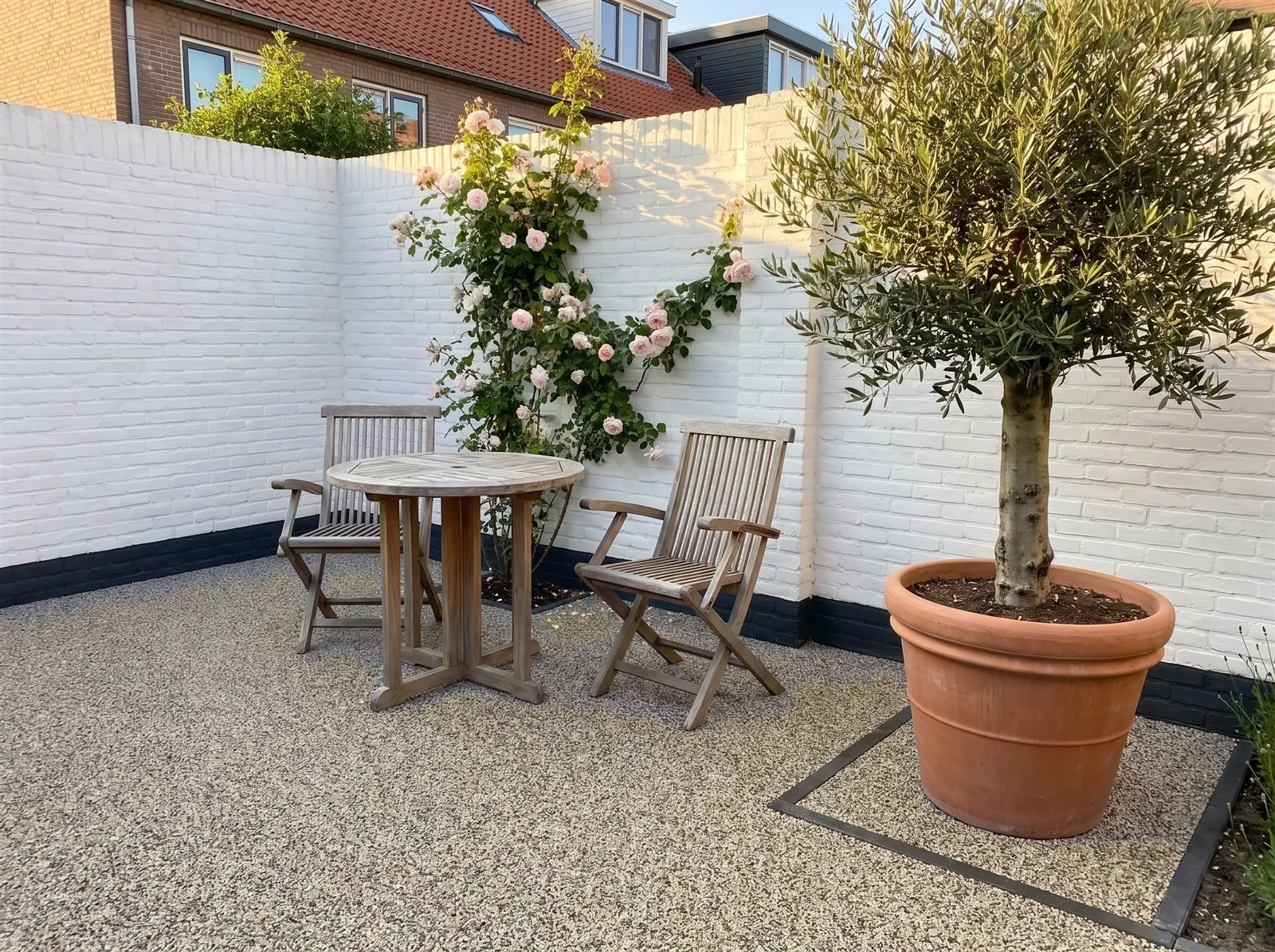 Sfeerimpressie: harsgebonden grind in Dapple Grey – als ommuurde patio met een olijfboom