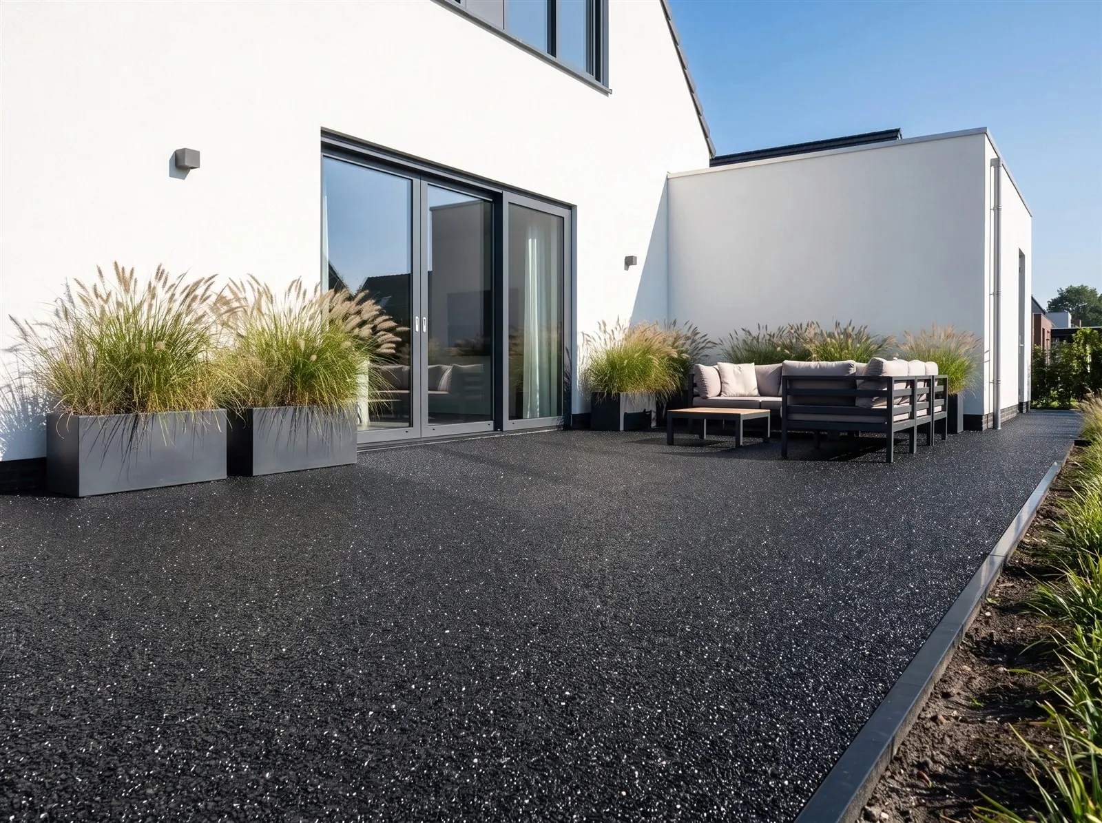 Sfeerimpressie: harsgebonden grind in Deep Black – als terras bij een moderne witte woning
