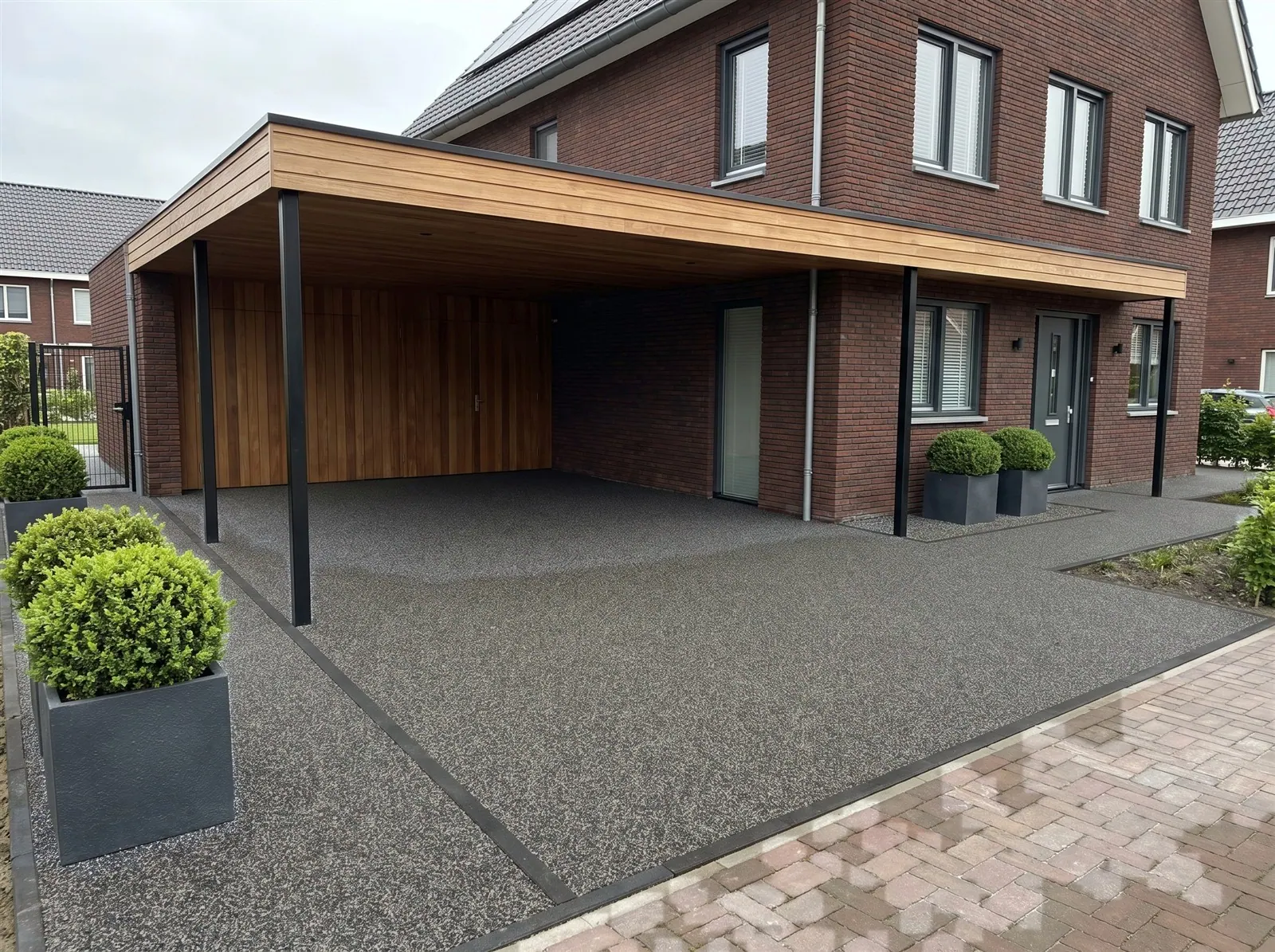 Sfeerimpressie: de vloer onder een carport, doorlopend naar de voordeur met harsgebonden grind in Mystic Grey