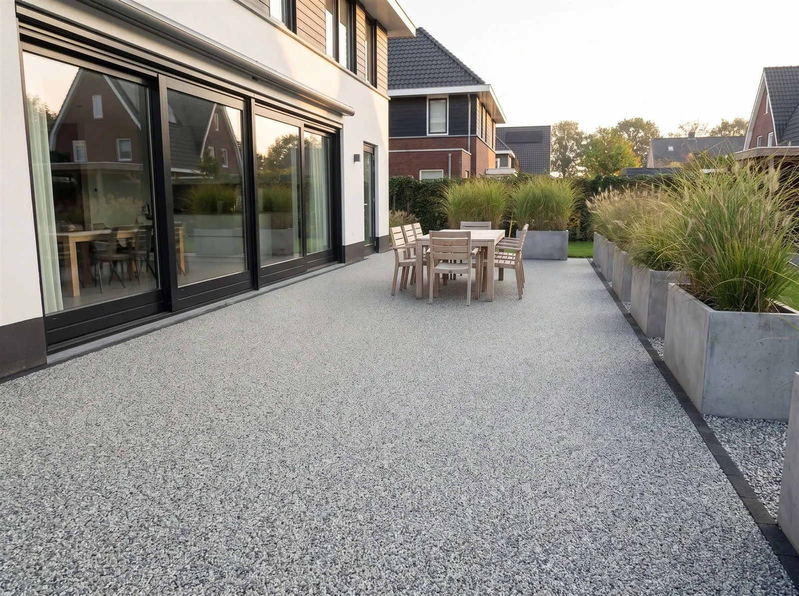Sfeerimpressie: een ruim terras achter een moderne woning met grote schuifpuien met harsgebonden grind in Azuro Blue